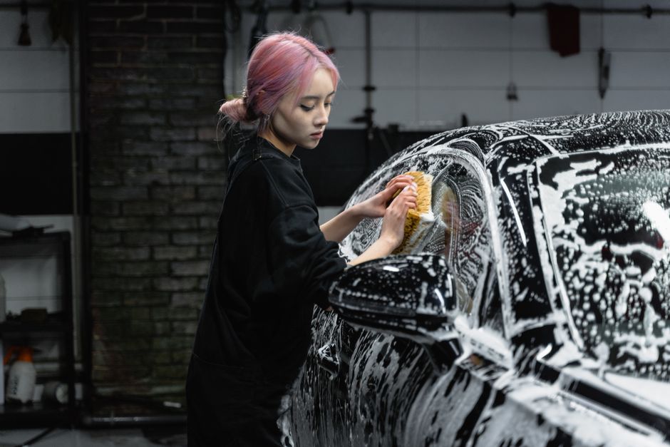 Professional car wash worker smiling and detailing a vehicle